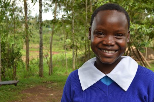 Young girl in blue school dress smiling to camera